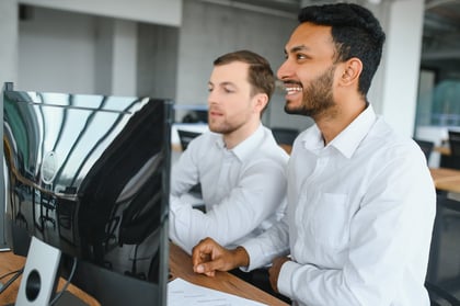 two-men-sitting-at-office-monitor
